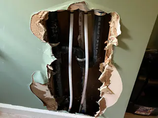 A wall opened behind a laundry area to reach the washing machine water lines in Carthage