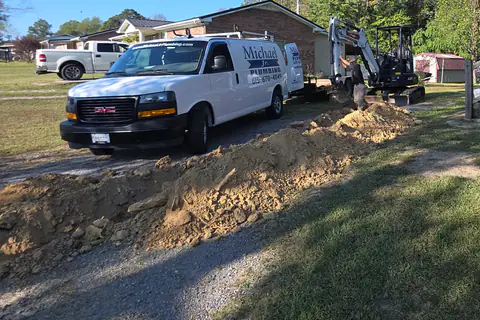 Our white van parked at a main water line replacement, with the mini excavator and a fresh trench behind it