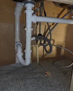 White PVC drain piping and a P-trap under a double sink