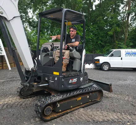 Michael Jr. at the controls of his mini excavator, our van parked behind him.