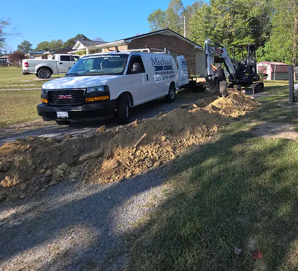 Our white Michael Jr. Plumbing van and our mini excavator at a main water line job.