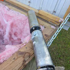 A pulled submersible well pump resting on the edge of a well house.