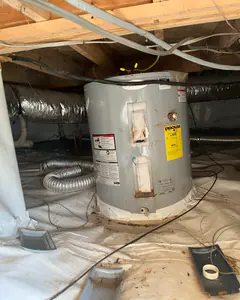 A new electric water heater set on the vapor barrier in a crawlspace.