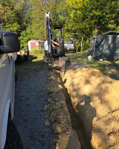 A long fresh trench for a new main water line, our mini excavator at the far end.